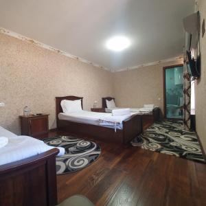a hotel room with two beds and wooden floors at Sherxan House in Samarkand