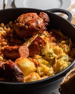 a pan full of food with meat and potatoes at Hotel Aroi Bierzo Plaza in Ponferrada
