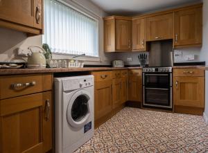 a kitchen with wooden cabinets and a washing machine at Number 4 in Fort William