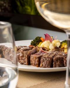 a plate of steak and vegetables with a glass of wine at Hotel Aroi Bierzo Plaza in Ponferrada