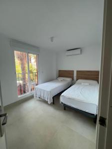 2 camas en una habitación con ventana en CASITA EN LA RIBERA en Almuñécar