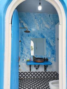 a bathroom with a blue wall with a sink and a toilet at Cloud9 Glamping & Cafe in Xuân Trường