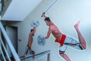a mural of two men lifting weights in a room at DREAMS AIRPORT RESIDENCY in Nedumbassery