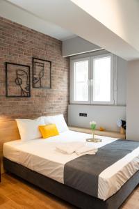 塞萨洛尼基Valaoritou 3 Luxury Rooms的一间卧室设有一张带砖墙的大床
