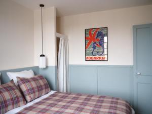 Schlafzimmer mit einem Bett mit einer karierten Decke und einem Poster in der Unterkunft La suite Armel proposé par escaleasaintbriac in Saint-Briac-sur-Mer