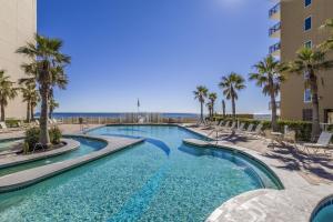 a swimming pool with palm trees and a building at Crystal Tower 404 in Gulf Shores