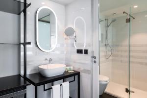 uma casa de banho branca com um lavatório e um chuveiro em Residence Inn Ghent by Marriott em Gent