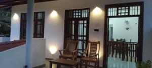a room with two chairs and a balcony with windows at Villa 142 in Weligama
