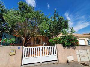 a white fence in front of a house with a tree at Le Salvador - maisonnette pour 4 in Sigean +4 photos