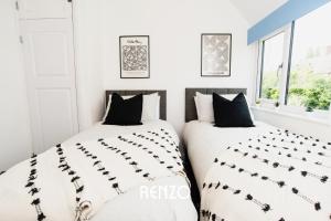 two beds in a bedroom with white walls and windows at Cosy 3-bed Home in Nottingham by Renzo, Driveway for 2 Cars, Perfect for Contractors! in Nottingham