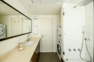 een badkamer met een wastafel en een wasmachine bij Chic 2BR Apt w Large Windows in Tel Aviv Old North Sea N' Rent in Tel Aviv