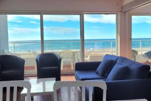 Una sala de estar con un sofá azul y una mesa y sillas. en Le Front de mer - vue imprenable, en Port-la-Nouvelle