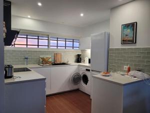 Una cocina con gabinetes blancos y lavadora y secadora. en Le Front de mer - vue imprenable, en Port-la-Nouvelle