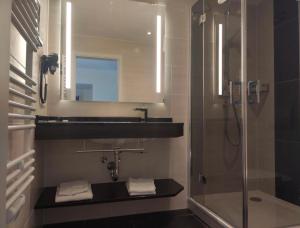 a bathroom with a shower and a sink and a mirror at Schlosshotel Rheinsberg in Rheinsberg
