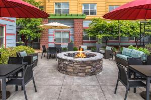un patio con una hoguera, mesas y sombrillas en Residence Inn by Marriott Portland North, en Portland