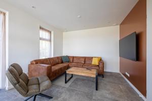 sala de estar con sofá marrón y TV en De Bunders Texel, en De Cocksdorp