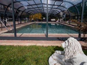 eine Statue vor einem Pool in der Unterkunft Domaine aux Lions - Piscine Tennis 20 min Deauville in Fauguernon