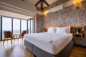 a bedroom with a large bed and a stone wall at Marlo Ayvalık 12 Plus Adult Only in Ayvalık