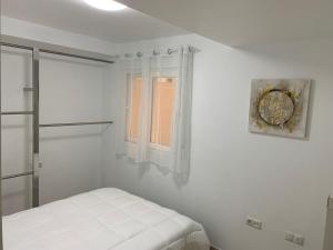 a white bedroom with a bed and a window at Apartamento Center Playa Almerimar in Almerimar