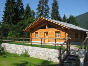 a log cabin with a stone wall in front of it at Chalet Camping Faè 4 - Trilocale in Madonna di Campiglio