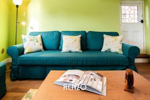 a blue couch in a living room with a table at Cosy 1-bed Cottage in Stoke Bardolph, Nottingham by Renzo, Stunning Countryside Location! in Burton Joyce