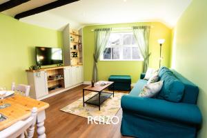 a living room with a blue couch and a table at Beautiful 1-bed Cottage in Stoke Bardolph, Nottingham by Renzo, Stunning Countryside Location! in Burton Joyce