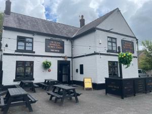 Ye Olde Original Withy Trees في Bamber Bridge: مبنى أبيض مع طاولات نزهة أمامه