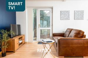 a living room with a brown leather couch and a tv at Cosy 1-bed Annexe in West Bridgford, Nottingham by Renzo, Free Driveway Parking! in Nottingham