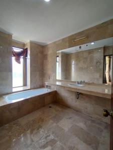 a bathroom with a tub and a sink and a mirror at Villa Bukit Danau Lot 14 in Cinengangirang