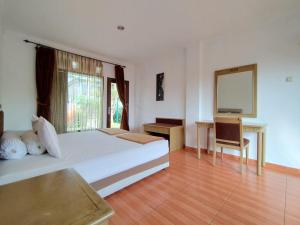 een slaapkamer met een bed, een bureau en een televisie bij Villa Bukit Danau Lot 14 in Cinengangirang