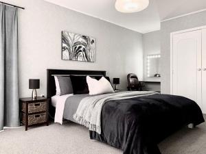 a black and white bedroom with a bed and a desk at M&K Home with central heating, 4 bedrooms, by Chartwell Shopping Centre in Hamilton