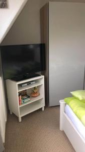 einen Flachbild-TV auf einem Stand in einem Schlafzimmer in der Unterkunft Seemöwe Wohnung in Rostock