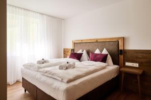 a bedroom with a large white bed with purple pillows at Alpenstolz Damüls Haus 3 - Stilvoll urlauben in den Bergen in Damuls