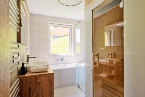 a bathroom with a sink and a tub and a window at Alpenstolz Damüls Haus 3 - Stilvoll urlauben in den Bergen in Damuls