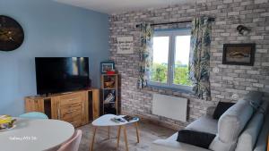 ein Wohnzimmer mit einem Sofa und einem TV in der Unterkunft La maison entre deux plages,vue sur mer classée 4 étoiles in Criel-sur-Mer