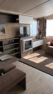 a living room with a television and a living room with a couch at 3 BEDROOM CARAVAN ON ST OSYTH BEACH HOLIDAY PARK WITH FREE Wfi AND PARKING in Saint Osyth