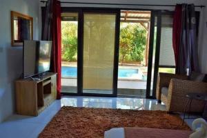 a living room with a television and a view of a pool at Villa O'Sables in Pointe aux Sable