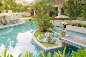 Dewa Phuket Resort & Villas في شاطئ ناي يانغ: وجود امرأتين جالستين على كراسي بجوار مسبح في المنتجع