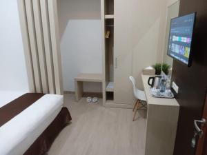 a hotel room with a bed and a desk with a television at Dawala Hotel in Sudiang +19 photos
