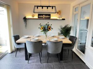 a dining room with a table with chairs and flowers at Large 4 Bed, Central Oxford, Games Area, On-Site Parking in Oxford