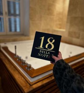 een persoon die een bord voor een bad omhoog houdt bij Bella Notte Spa in Dijon