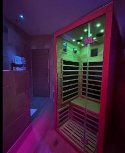 Habitación con ducha acristalada con luces moradas. en Bella Notte Spa en Dijon