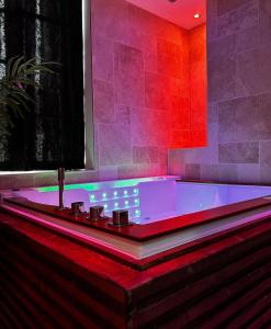 een badkamer met een bad met rode en paarse verlichting bij Bella Notte Spa in Dijon +1 foto