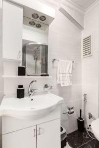 ein weißes Badezimmer mit einem Waschbecken und einem Spiegel in der Unterkunft Practical and Cozy Flat Near Taksim İstikal in Istanbul