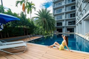 a woman in a yellow dress sitting next to a swimming pool at Bhukitta Boutique Hotel Phuket Town in Phuket Town