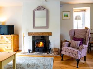 a living room with a fireplace and a chair and a mirror at Pass the Keys Delightful Millend Cottage with Parking and Patio in Northleach