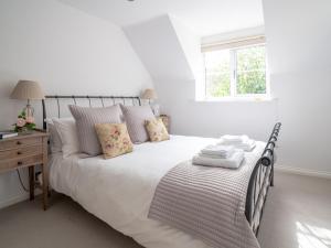 biała sypialnia z łóżkiem i oknem w obiekcie Pass the Keys Delightful Millend Cottage with Parking and Patio w mieście Northleach