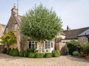 a house with a tree in the front of it at Pass the Keys Delightful Millend Cottage with Parking and Patio in Northleach