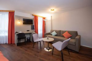 a living room with a couch and a table and chairs at Hotel Alex Business & SPA in Naters