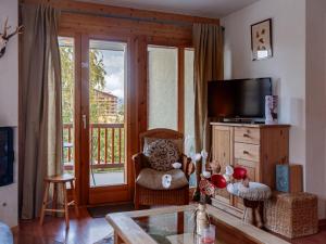 a living room with a television and a chair at Apartment Les Chouettes 4 by Interhome in Nendaz